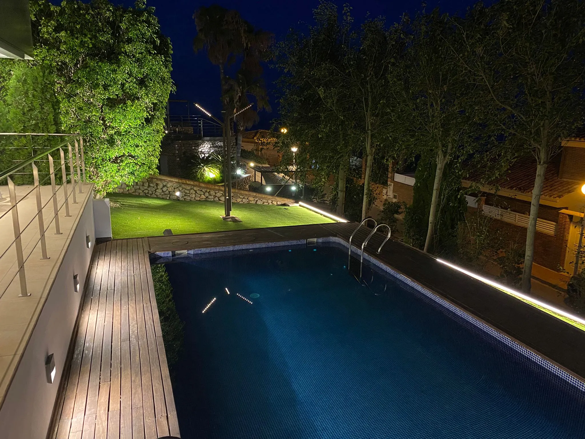 Piscina y jardín con iluminación exterior nocturna